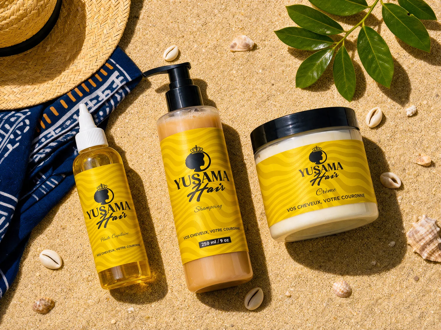 Huile, shampoing et crème Yusama Hair posés sur le sable